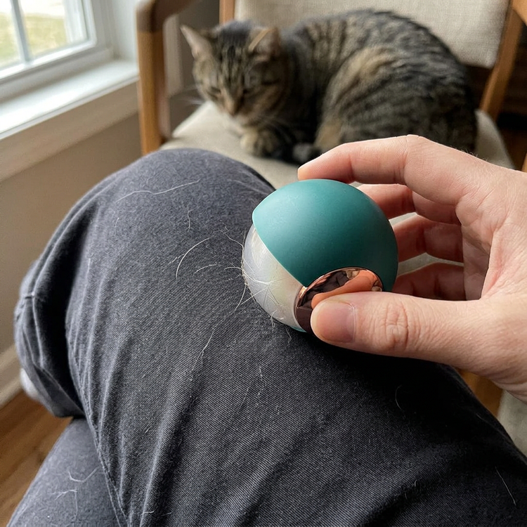 Green lint roller being used to pick up pet hair from dark trousers